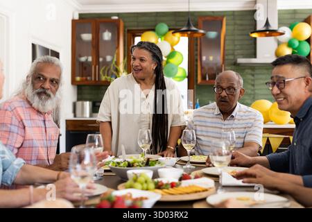 Verschiedene Seniorenfreunde genießen gemeinsam ein Mittagessen, teilen Geschichten und lachen zu Hause. Freundschaft, ältere Menschen, Essen, Party, Freundschaft, Unterhaltung || Modell veröffentlicht Stockfoto