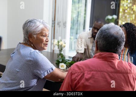 Familientreffen zu Hause, verschiedene Gruppen genießen Gespräche am Esstisch. Zweisamkeit, Feier, Gemeinschaft, Abendessen, Bindung || Model veröffentlicht Stockfoto