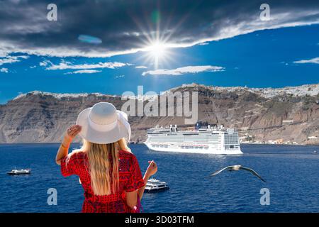 Santorin Kreuzfahrt: Frau in Hut beobachtet das Schiff und Santorin. Lebhaftes Leben auf den griechischen Inseln, Reisen und Tourismus. Griechenland. Stockfoto