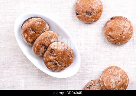Lebkuchen aus Früchten, traditioneller deutscher Lebkuchen in einer weißen Schüssel, auf Leinen. Weihnachtliche Gewürzkekse mit kandierten Fruchtstücken und glasierter Zucker. Stockfoto