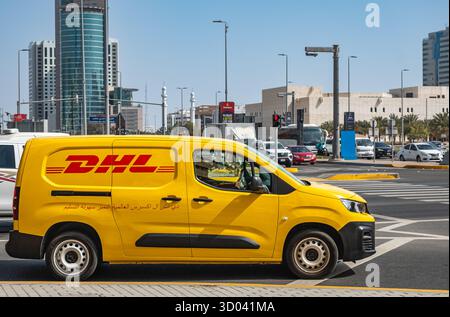 Ein gelber DHL-Kurierdienst-Lieferwagen ist eilig mit der Lieferung. DHL-Lieferwagen auf der geschäftigen Straße Abu Dhabi VAE. Reisefoto, niemand, Straßenfoto Stockfoto