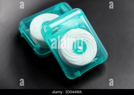 Zahnseide in grünen Kunststoffbehältern auf schwarzer Keramik-Nahaufnahme Stockfoto