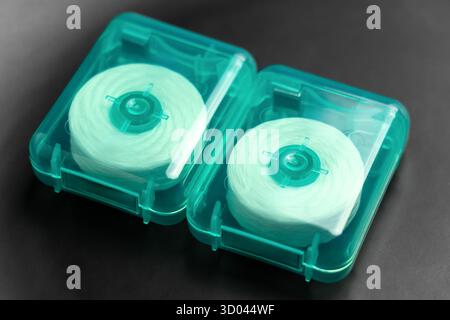 Zwei Rollen Zahnseide in grünen Kunststoffkisten auf schwarzer Nahaufnahme Stockfoto