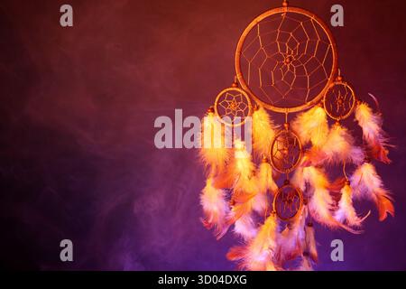 Schöner Traumfänger und Rauch in Farbe hell auf dunklem Hintergrund. Leerzeichen für Text Stockfoto
