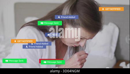 Sitzende reife Frau hustet in die Hand auf dem Bett im Schlafzimmer, mit farbenfrohen Benachrichtigungsgrafiken Stockfoto