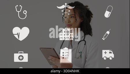 Ärztin, die Tablette überprüft, Laborkittel und Stethoskop im Studio trägt, mit medizinischen Ikonen Stockfoto