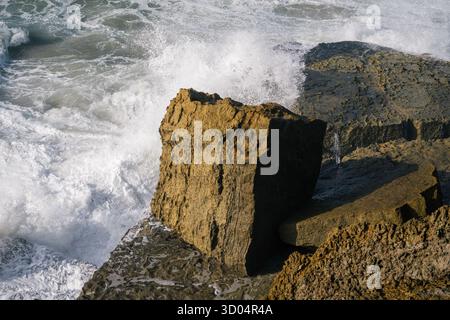 Starke Wellen des Atlantiks brechen am 16. Oktober 2025 im Praia das Macas Sintra Lissabon District Portugal gegen zerklüftete Küstengesteine. Stockfoto