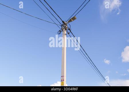 Russland, Sankt Petersburg, 23.08.2025 Versorgungsmast mit vielen elektrischen Kabeln und Straßenbeleuchtung vor klarem blauem Himmel im Freien. Stromleitungsinfrastruktur Stockfoto