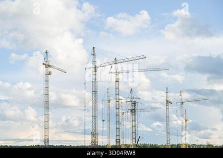 Russland, Sankt Petersburg, 23.08.2025 zahlreiche Baukräne, die sich in den Himmel über einem Wald erstrecken, symbolisieren Entwicklung und Stadterweiterung. B Stockfoto