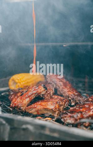 Rippchen werden auf einem Grill gekocht, von dem eine Sauce tropft. Die Sauce ist wahrscheinlich eine Barbecue-Sauce, die ein beliebtes Gewürz für gegrilltes Fleisch ist. Stockfoto