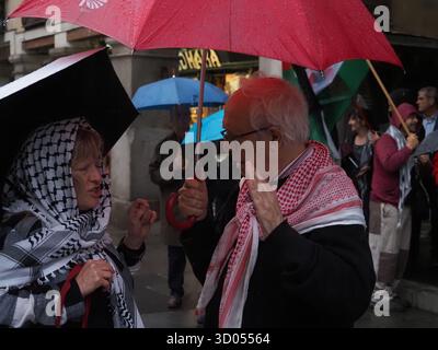 Madrid, Madrid, Spanien. Oktober 2025. Ein Paar mit Regenschirmen und Keffiyehs steht im Regen vor dem Außenministerium während einer Kundgebung, nachdem Israel den Waffenstillstand gebrochen hatte. (Kreditbild: © Aaron Heredia/ZUMA Press Wire) NUR REDAKTIONELLE VERWENDUNG! Nicht für kommerzielle ZWECKE! Stockfoto