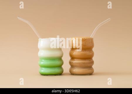 Matcha Latte und Kaffee vor beigefarbenem Hintergrund. Minimales Matcha vs. Kaffeekonzept. Trendige natürliche Energie und gesunde Getränke. Stockfoto