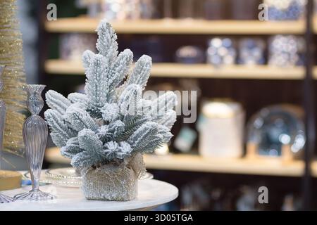 Wunderschöner kleiner, schneebedeckter Weihnachtsbaum in einem Souvenirladen. Weihnachtsdekoration Stockfoto