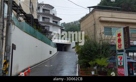 SEOUL, SÜDKOREA - 11. OKTOBER 2025 - Eine Straße in Achiul Village, Seoul, mit modernen Gebäuden und einem 7 Eleven an einem regnerischen Tag Stockfoto