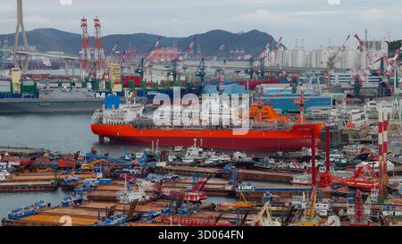 BUSAN, SÜDKOREA - 9. OKTOBER 2025 - Ansicht des Industriehafens mit vielen Schiffen, Frachtschiffen und Kränen in einer stark frequentierten Hafenanlage Stockfoto