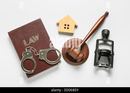 Richterlicher Hammer mit Gesetzbuch, Handschellen, Stempel und Hausfigur auf weißem Hintergrund Stockfoto