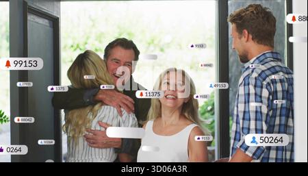 Begrüßung eines älteren Paares, das die erwachsene Tochter vor der Tür umarmt, mit Glasplatten und Benachrichtigungssymbolen Stockfoto