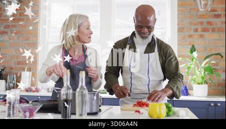 Ein Paar trägt Schürzen, rührt einen Topf und schneidet Paprika in der Küche, mit Schneidebrett Stockfoto