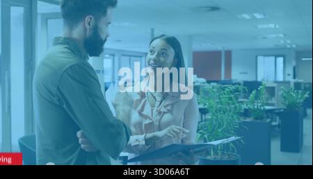 Weibliche Managerin in rosa Bluse, die auf Mappe zeigt und männlicher Kollege, der im Großraumbüro zuhört Stockfoto