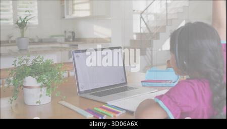 Mädchen in magentafarbenem Hemd mit Kopfhörern am Küchentisch mit Laptop und Bleistiften, Kopierraum Stockfoto