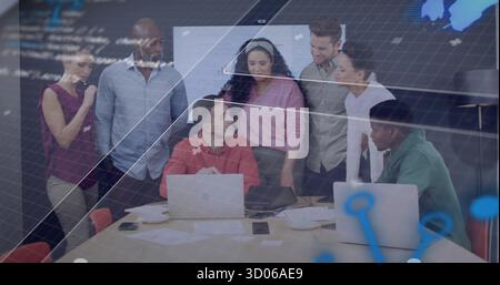 Teamkollegen diskutieren am Tisch im Konferenzraum mit Laptops, Papieren und Kaffeetassen Stockfoto