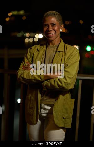 Selbstbewusste lächelnde Frau mit überkreuzten Armen in der Nacht Stockfoto
