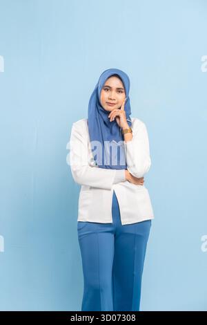 Porträt eines besorgten asiatischen muslimischen Arztes oder einer Krankenschwester, der tief denkt, isoliert einen blauen Hintergrund. Stockfoto
