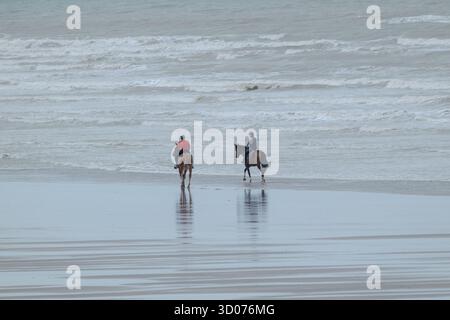 Friedlicher Reiten am Strand - ruhige Reitmomente am Meer unter einem bewölkten Himmel in natürlichem Licht Stockfoto