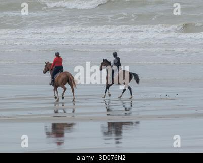 Friedlicher Reiten am Strand - ruhige Reitmomente am Meer unter einem bewölkten Himmel in natürlichem Licht Stockfoto