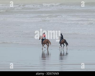 Friedlicher Reiten am Strand - ruhige Reitmomente am Meer unter einem bewölkten Himmel in natürlichem Licht Stockfoto