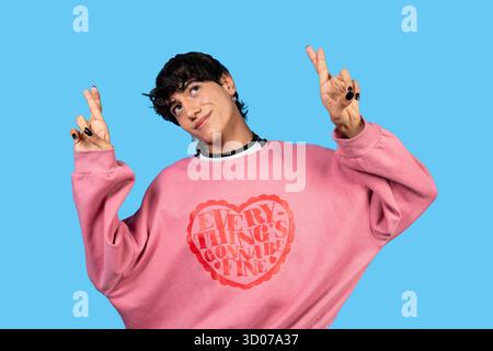 Junge Person lächelt, während sie die Finger drückt, in der Hoffnung auf Glück und ein positives Ergebnis Stockfoto