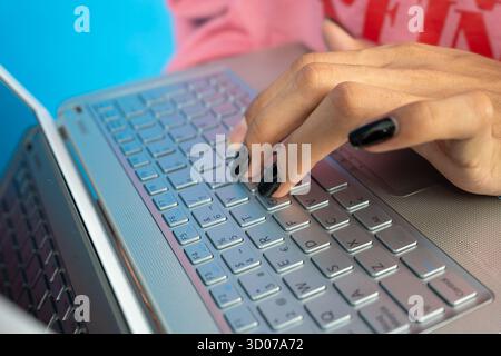 Frauenhand mit schwarzem nagellack auf einer Laptop-Tastatur Stockfoto