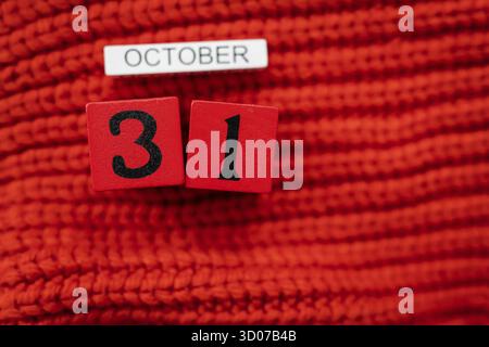 Holzwürfelkalender zeigt am 31. Oktober Halloween isoliert auf rotem Hintergrund rot gestrickter Pullover Stockfoto