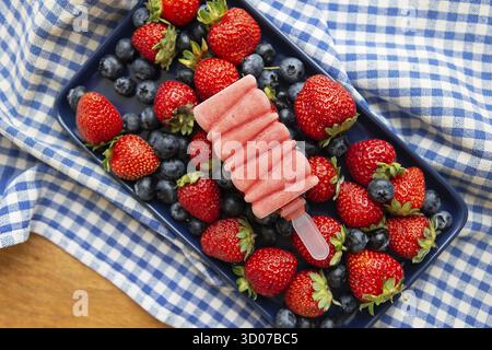 Köstliches Eis aus frischen Erdbeeren und Blaubeeren aus der Nähe liegt auf frischen Erdbeeren und Blaubeeren. Blau-Karokelnappe Stockfoto