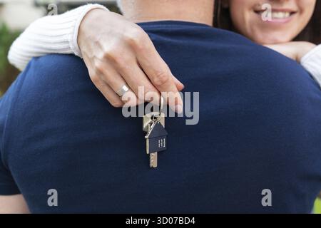 Glücklich lächelndes junges Paar genießt es, eine Wohnung zu kaufen, und das Paar zeigt die Schlüssel zu ihrem neuen Zuhause. Kauf eines Hauses Stockfoto