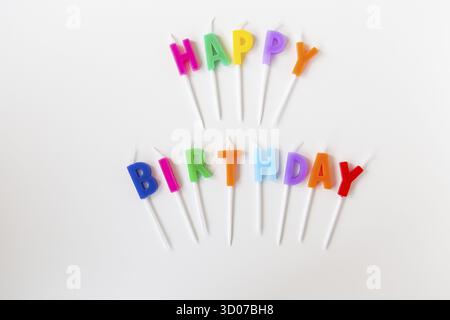 Bunte Kerzen mit der Aufschrift Happy Birthday isoliert auf weißem Hintergrund. Urlaubs- und Überraschungskonzept Stockfoto