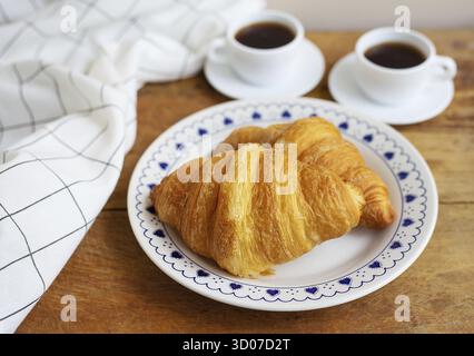 Frühstück im Bett, frische Croissants und eine Tasse Kaffee auf einem Holztablett Stockfoto
