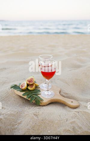 Weißes cape, Brille auf Holzbrett und Sand. Sommer-Picknick aus nächster Nähe Stockfoto