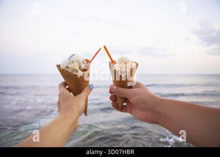 Zwei Hände halten leckeres Eis an einem Sommerstrand Stockfoto