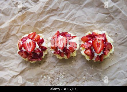 Sehr leckere Muffins mit frischen Erdbeeren liegen auf Kraftpapier Stockfoto