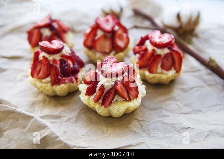 Sehr leckere Muffins mit frischen Erdbeeren liegen auf Kraftpapier Stockfoto