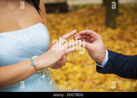 Die Hand des Bräutigams, die der Braut einen Ehering an den Finger legt Stockfoto