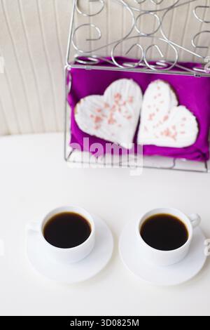 Zwei Tassen Kaffee und Kekse in Herzform auf einer rosa Serviette Stockfoto