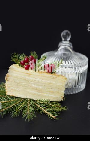 Ein Stück Kuchen verziert Baum und Beeren auf schwarzem Hintergrund, Untertasse mit Marshmallows Stockfoto