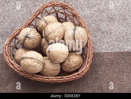 Walnüsse in der alten Weidenkorb auf Sackleinen Stockfoto
