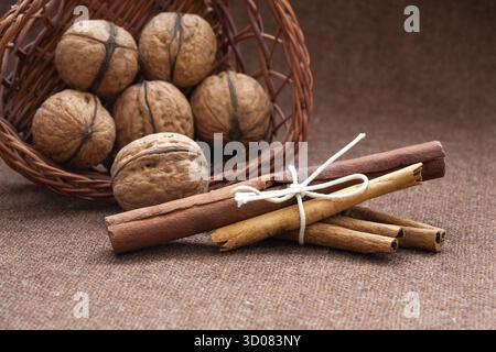 Walnüsse in einem Weidenkorb und Zimt, Sackleinen Hintergrund Stockfoto