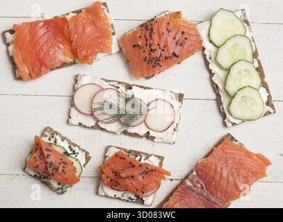 Blick von oben auf Kanapees und Sandwiches mit Lachs und Gemüse Auf Holzhintergrund Stockfoto