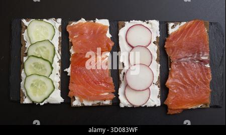 Blick von oben auf Sandwiches mit Lachs und Gemüse auf Schiefer Stockfoto