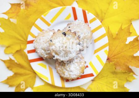 Farbige Cupcakes auf einem Teller und gelbe Herbstblätter Stockfoto