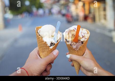 Schönes helles Eis mit verschiedenen Geschmacksrichtungen in den Händen von ein paar Stockfoto